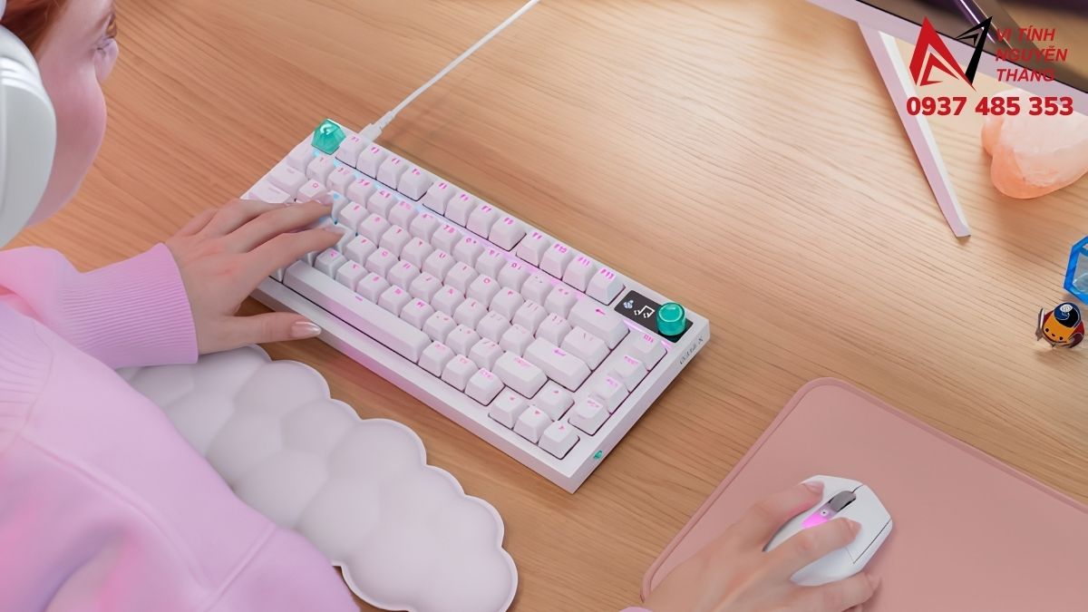 Bàn phím cơ màu hồng pastel đặt cạnh hộp quà và hoa trên bàn làm việc